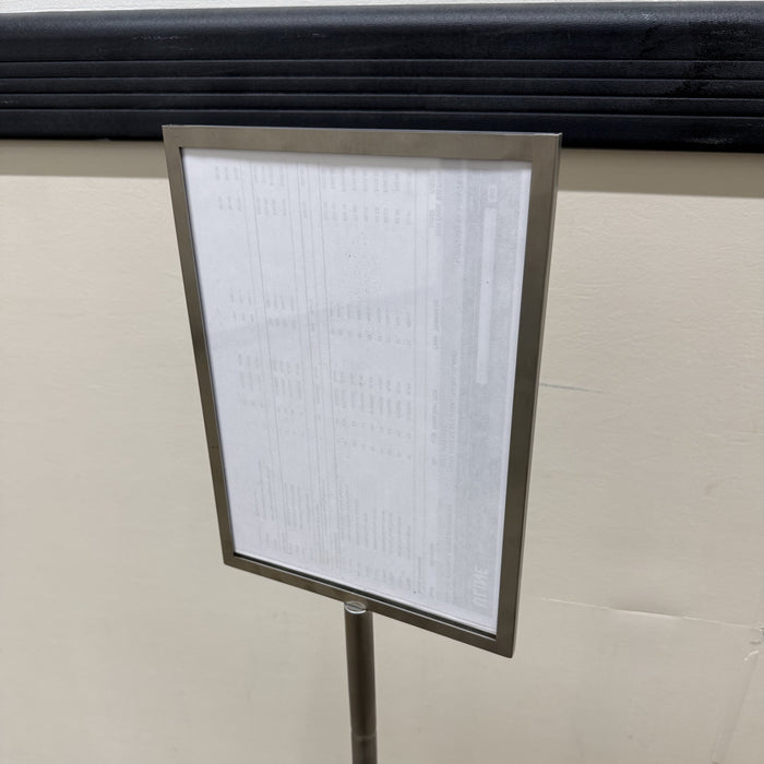 Angled close-up of a stainless steel menu frame on a pole stand.