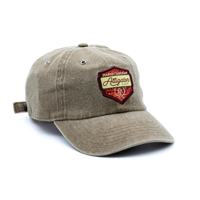 Tan cotton twill 6-panel country cap with an Alligator Camp patch and metal eyelets on a white background.