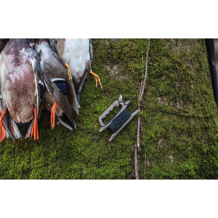 Rig 'Em Right jerk rig with black nylon line on a brown plastic winder next to duck decoys on a mossy tree.