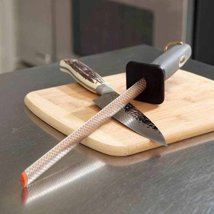 10-inch diamond-coated oval sharpening rod with a grey handle and hand guard resting on a wooden cutting board with a knife.