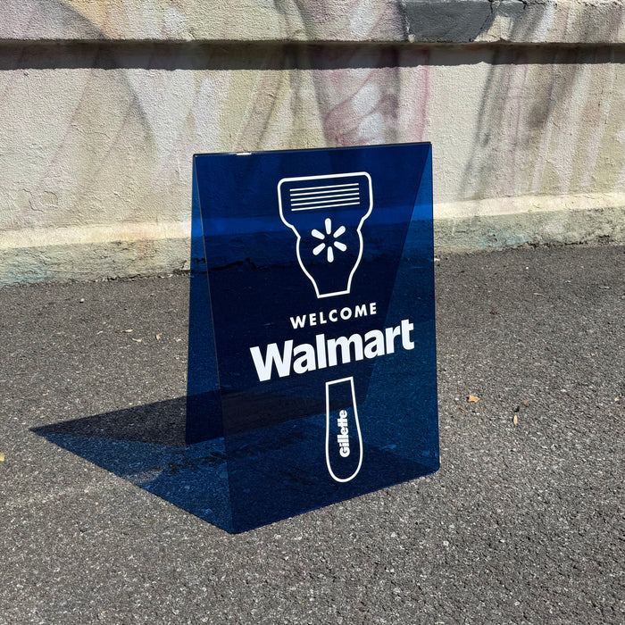 Transparent blue acrylic A-frame sign with a razor graphic and Welcome Walmart lettering.