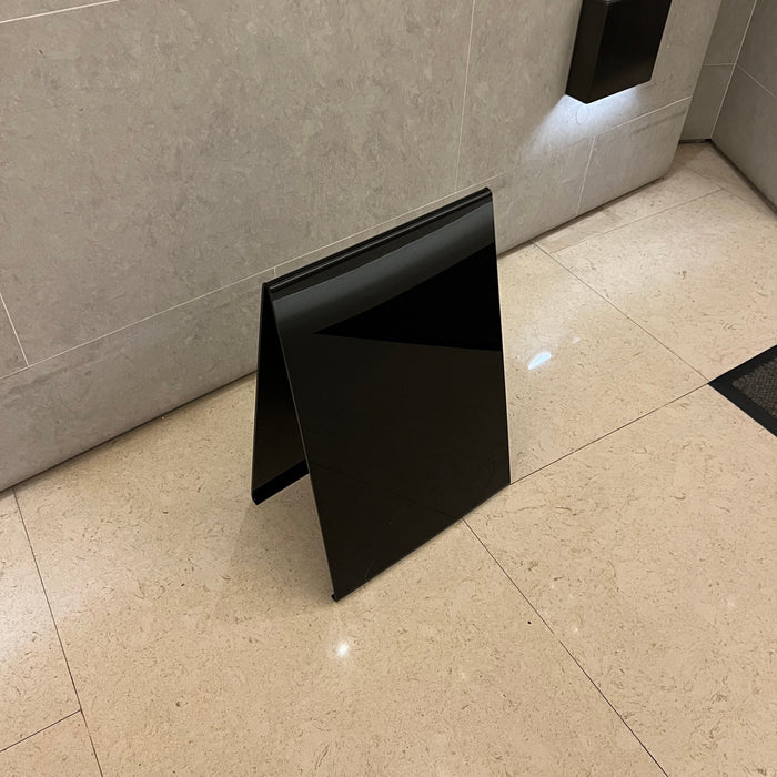 High angled view of a blank black opaque acrylic A-frame sign.