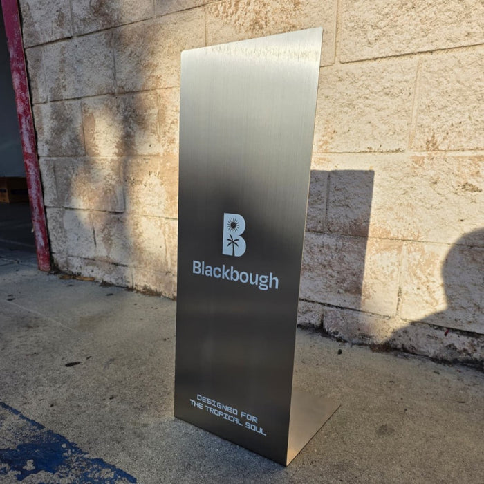 Slanted stainless steel floor sign with Blackbough branding outdoors.