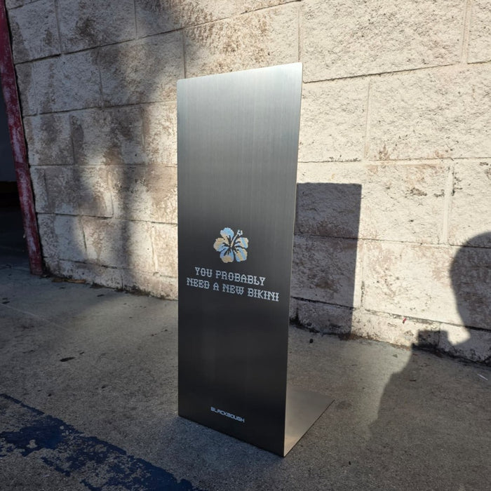 Angled view of a slanted stainless steel sign with The Peninsula Tokyo lettering.