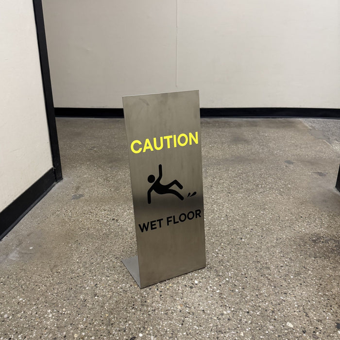 Stainless steel floor sign with yellow Caution lettering and a wet-floor symbol.