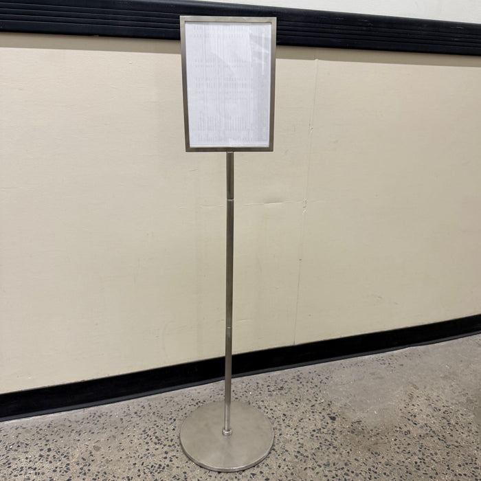 Full view of a stainless steel pole sign with a portrait menu frame and round base.