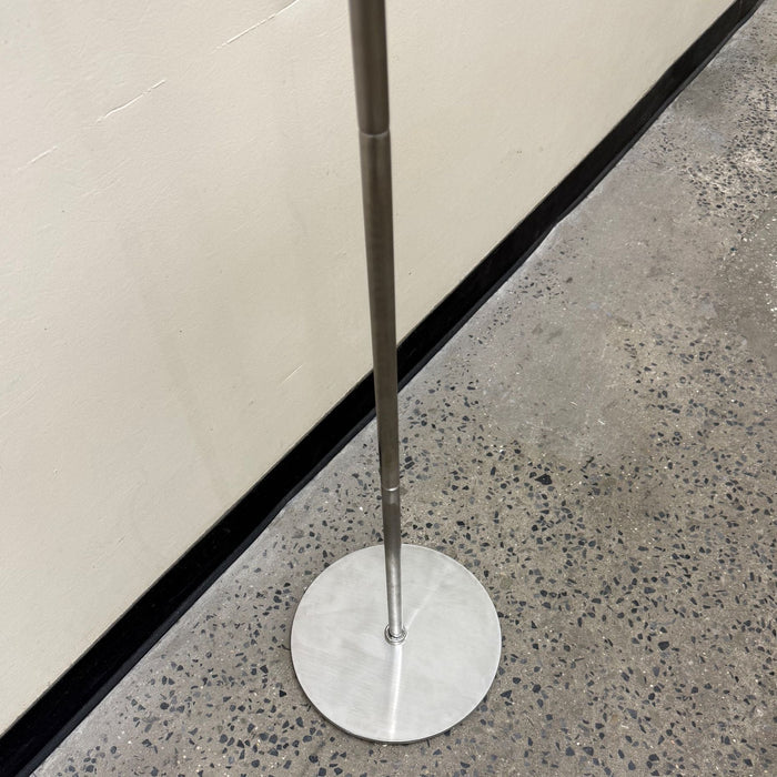 Close-up of the round base and lower pole of a stainless steel sign stand.