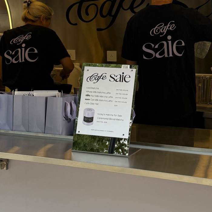 Mirrored tabletop stand displaying a Café Saie menu on a counter.