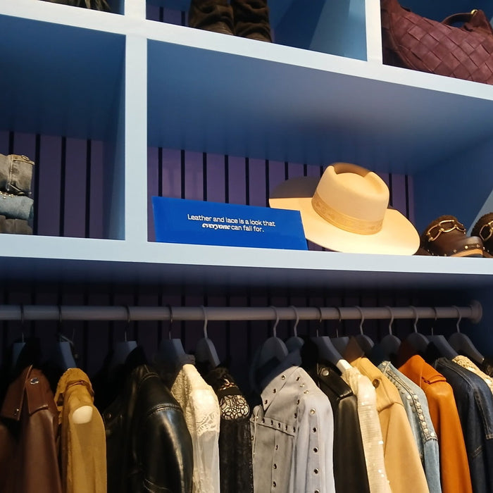Blue landscape acrylic sign on a shelf above a clothing rail.