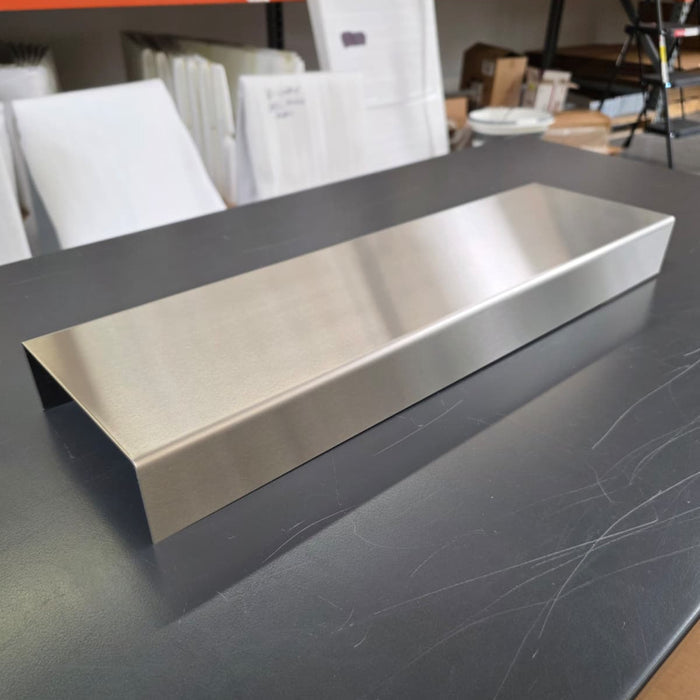 Angled view of a long stainless steel display riser on a worktable.