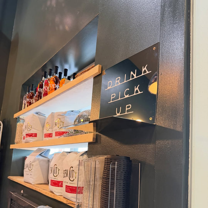 Mirrored Drink Pick Up wall shelf beside a café counter.