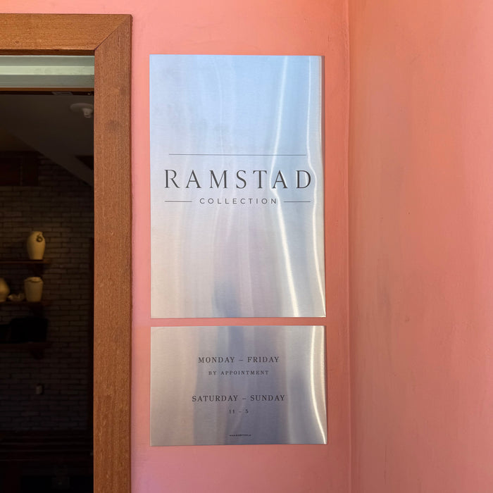 Two stainless steel Ramstad plaques mounted on a coral-colored wall.
