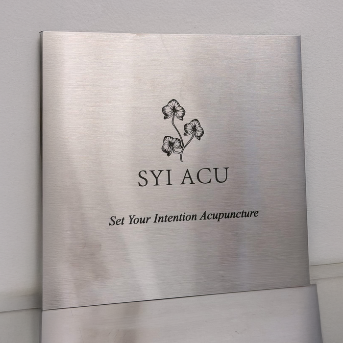 Square stainless steel plaque with SYI ACU branding and Set Your Intention Acupuncture lettering.