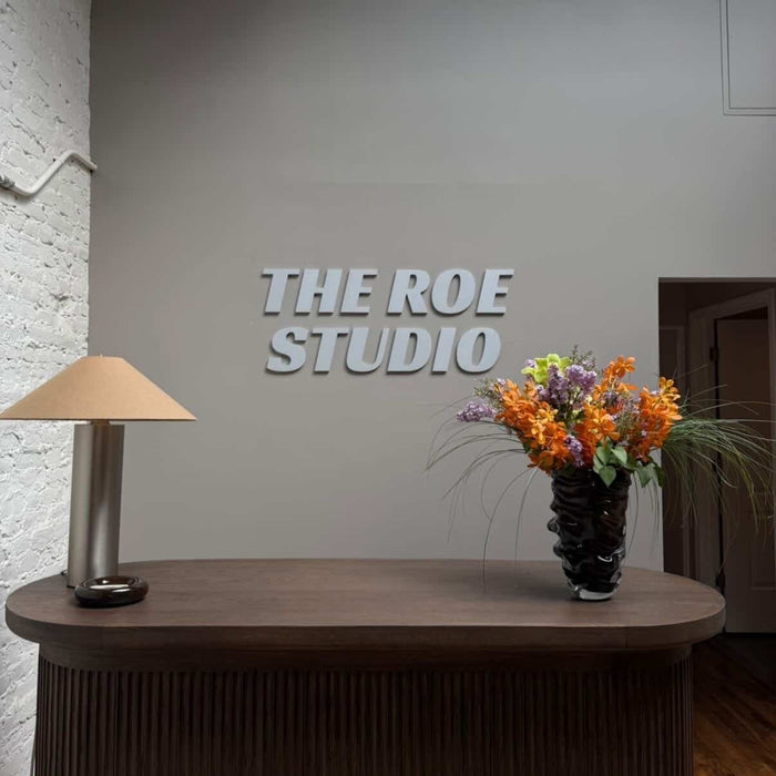 The Roe Studio aluminum wall lettering above a reception desk with flowers.