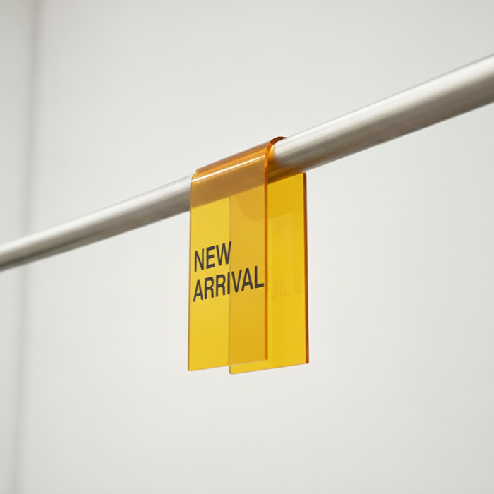 Yellow acrylic clothing rack sign clip with New Arrival lettering on a rail.