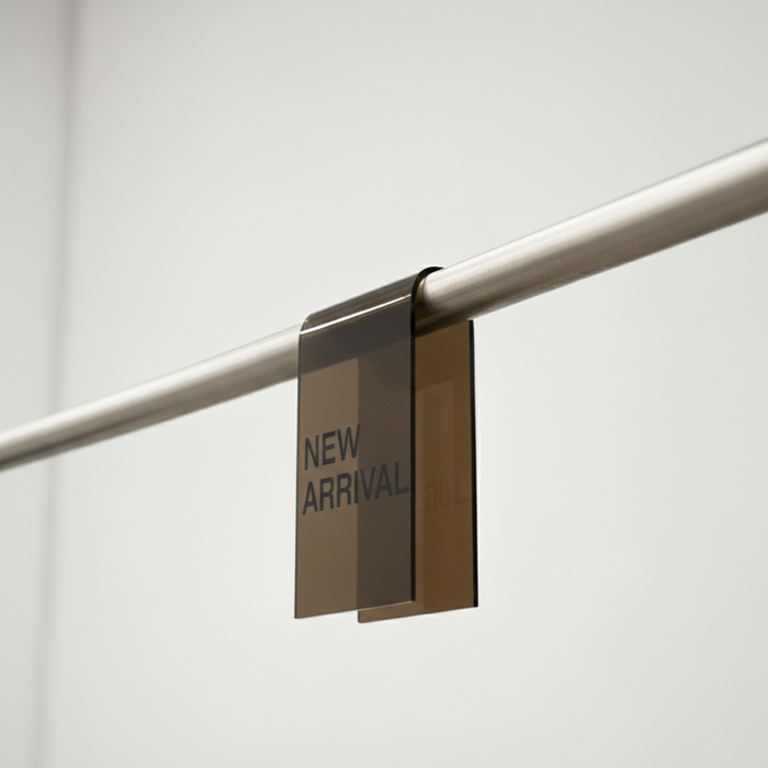 Bronze smoke acrylic clothing rack sign clip with New Arrival lettering on a rail.