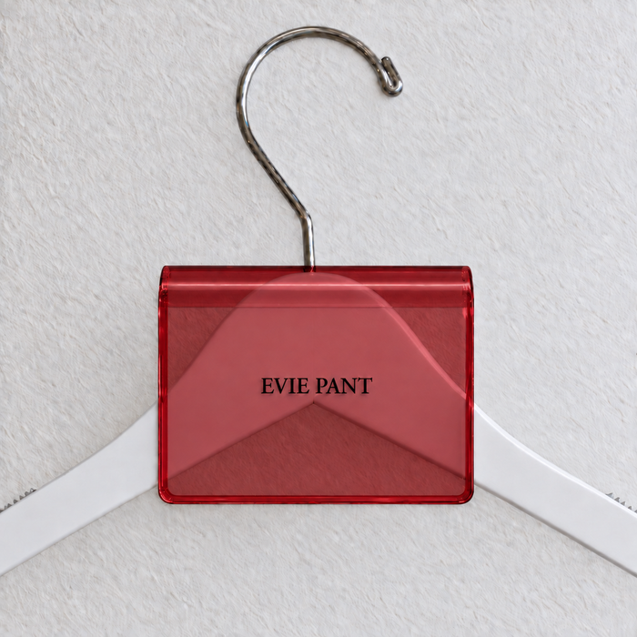 Red transparent acrylic hanger sign clip with soft edge reflections, resting on a white wooden hanger, with example EVIE PANT print