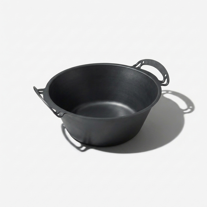 Seasoned iron pot with handles on a white background