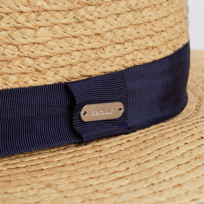 Barbour Lily straw boater hat with a navy grosgrain ribbon band and a branded silver metal logo plaque.