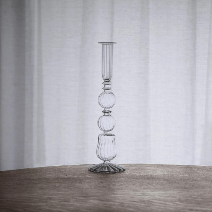 Clear glass 10.5-inch Emma candlestick holder with a delicate, ribbed, and spherical design on a wooden table.