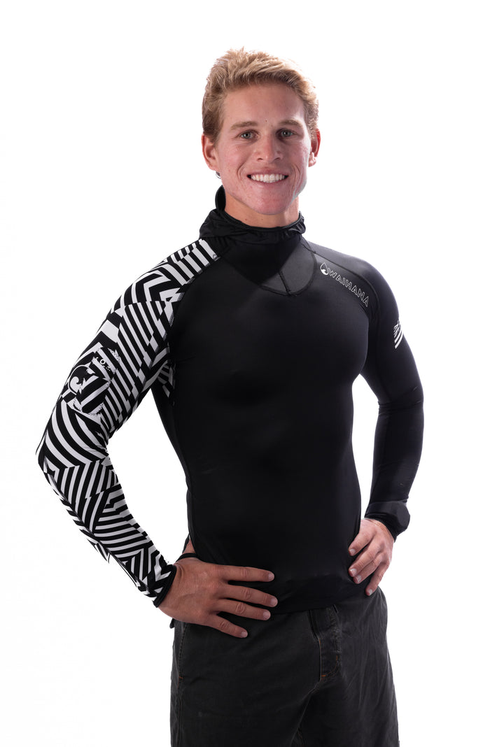 Smiling male model wearing the Waihana Black Carvico Hooded Surf Rashguard with a bold black-and-white geometric patterned sleeve, photographed against a clean white studio background.