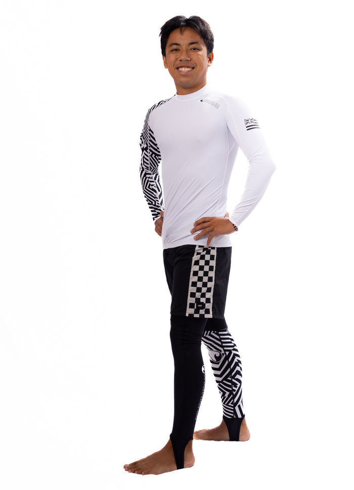 Male model wearing Waihana white long-sleeve rashguard and Black Carvico Lycra leggings with geometric and checkerboard patterns, shown in a full-body studio pose.