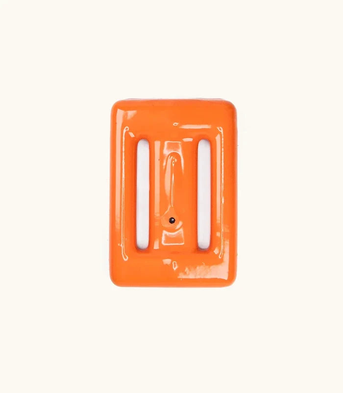 Bright orange vinyl-coated Clownfish dive weight by Bright Buoy Diving, showing two strap slots and a retaining pin, on a neutral cream background.