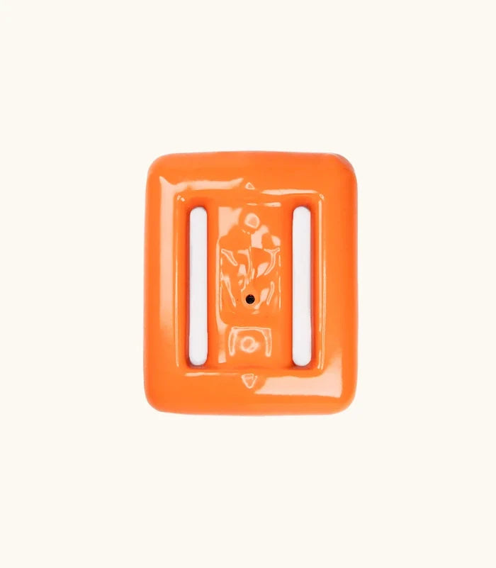 Bright orange coated Clownfish dive weight by Bright Buoy Diving, featuring two white rubber belt track inserts, photographed from above on a clean off-white background.