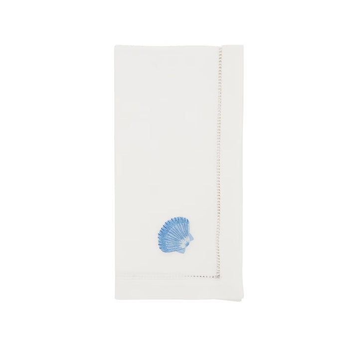 White 20-inch cotton napkin with blue embroidered seashell detail and delicate hemstitch border.