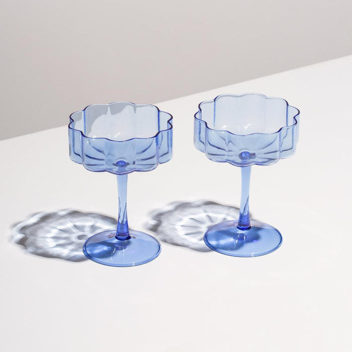 Set of two hand-blown blue borosilicate glass coupe glasses with elegant rippled edges and slender stems.