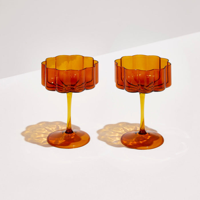 Set of two amber hand-blown borosilicate coupe glasses with elegant elongated stems and signature rippled edges.