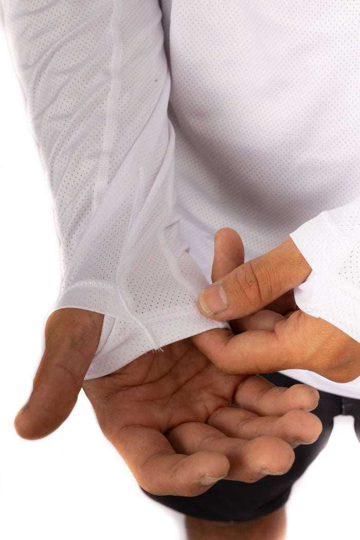 Close-up of a man's hands stretching the cuff of the Waihana Ghost Sun Shirt in Ghost White, highlighting the perforated breathable fabric and flexible fit.