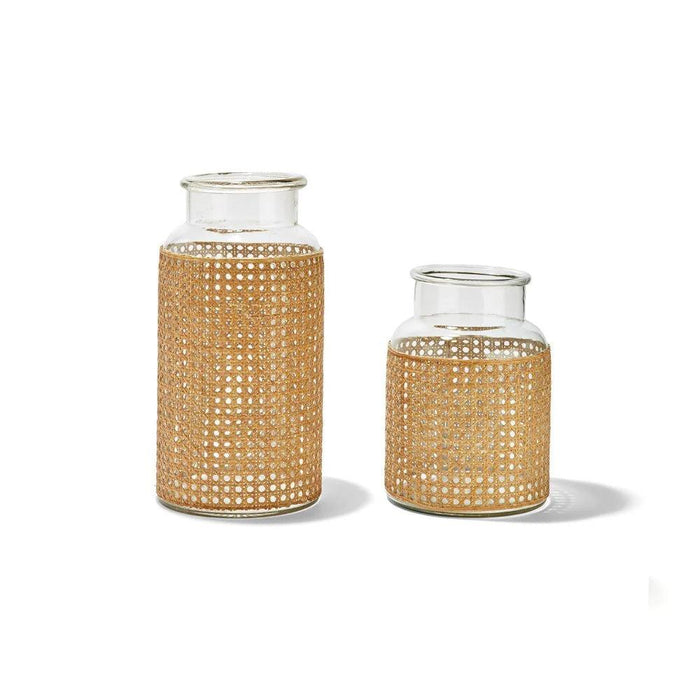 Two glass jars wrapped in natural woven cane webbing, featuring a tall and short cylindrical design.