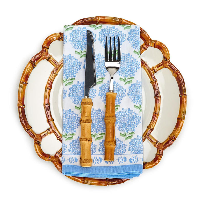 8.75-inch melamine salad plate with a decorative bamboo-style rim, topped with a blue hydrangea napkin and bamboo-handled cutlery.