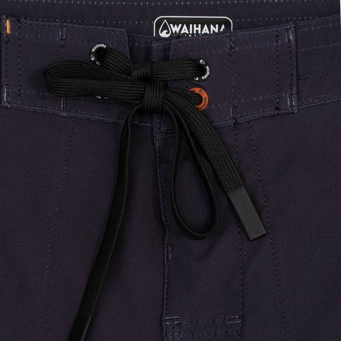Close-up of the waistband on Waihana Jet Black W1-PRO Board Shorts, featuring a black braided drawstring with branded white and orange eyelets and a Waihana logo patch.