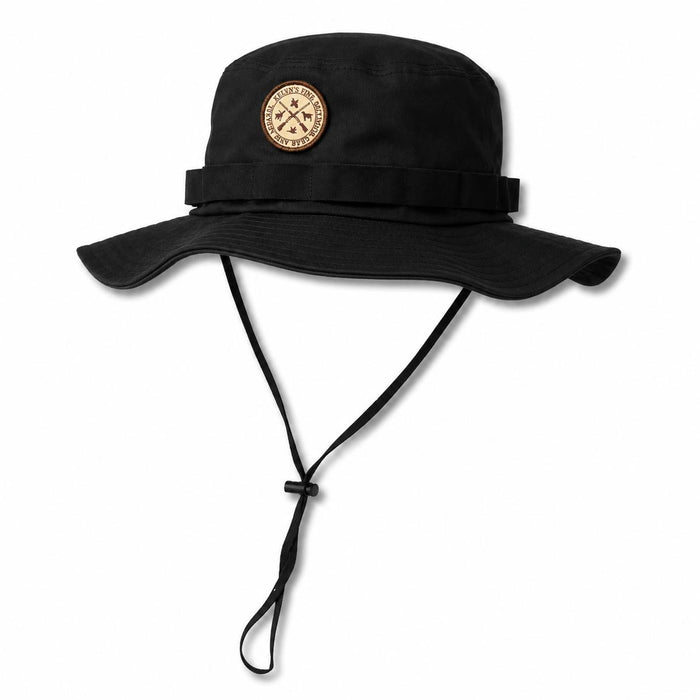 Black cotton twill boonie hat with a wide brim, adjustable chin strap, and a circular leather patch on the front.