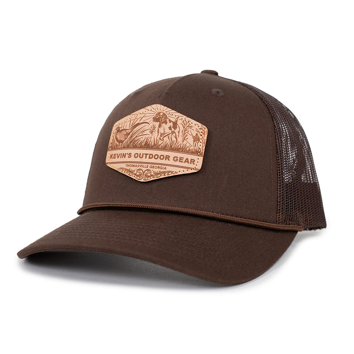 Brown Richardson 112 trucker cap featuring a leather etched patch with a pointer dog and Kevin's Outdoor Gear logo.