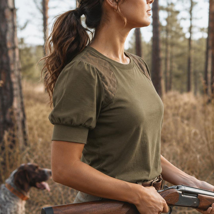 Olive green cotton shooting tee with puff sleeves and quilted shoulder patches worn in a field.