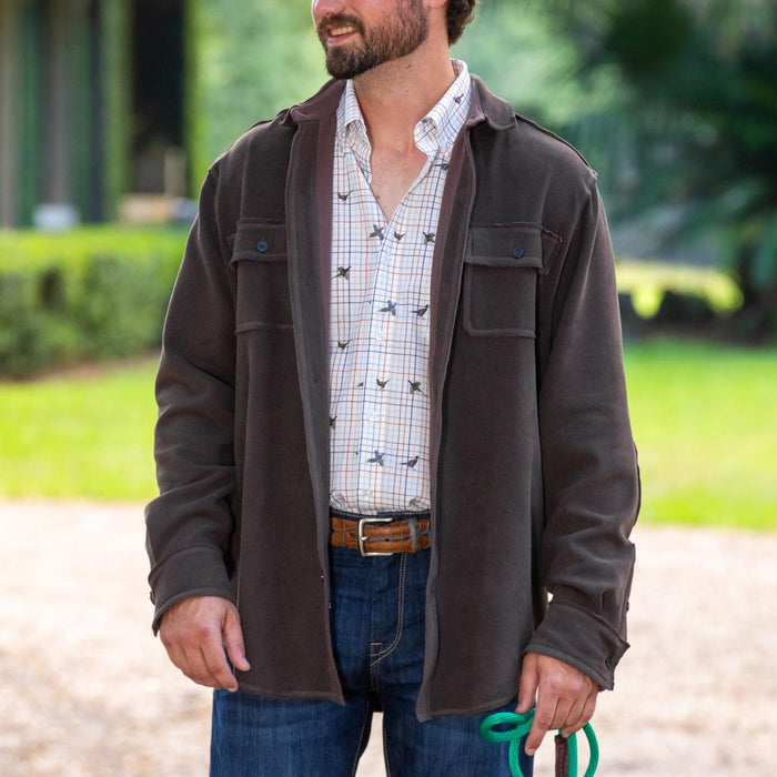 Man wearing a brown soft sueded shirt jacket over a patterned button-down shirt and blue jeans.
