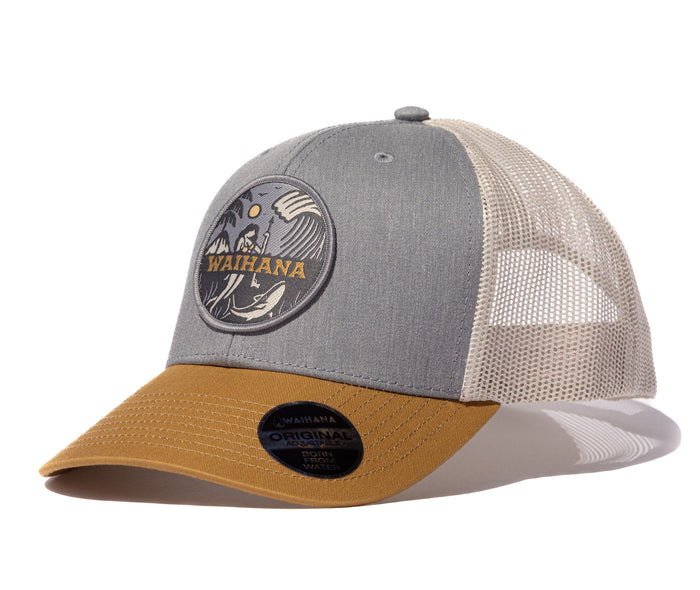 Waihana Lagoon Diver Trucker cap in heather grey with a beige mesh back and gold brim, showcasing a circular embroidered patch depicting a spearfisher underwater with a whale and crashing wave.