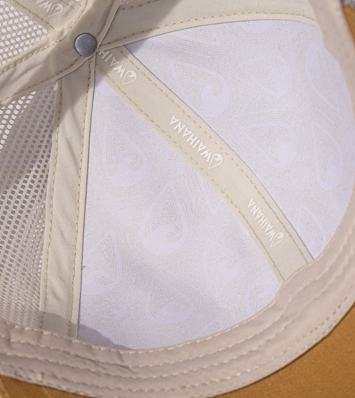 Interior close-up of the Waihana Lagoon Diver Trucker hat revealing a white topographic print lining, cream Waihana branded tape, mesh ventilation panel, and metal crown button.
