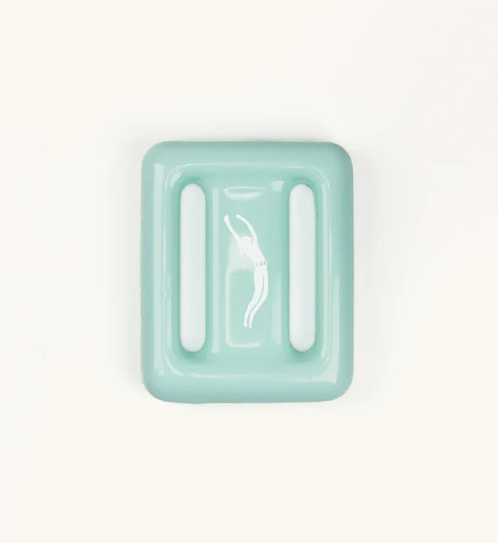Mint green Lanikai dive weight by Bright Buoy Diving with raised drainage ridges and a white freediver silhouette, shown from above on a white background.