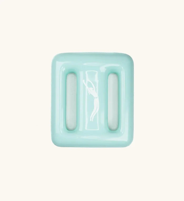Top-down view of a mint green Lanikai dive weight by Bright Buoy Diving, featuring three drainage slots and an embossed freediver silhouette on a clean off-white background.