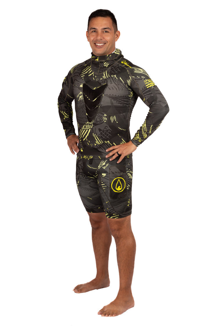 Male model wearing the Waihana Lime Fishbone Hooded Spearfishing Rashguard in a dark camo pattern with yellow-green accents, paired with matching shorts, on a white studio background.