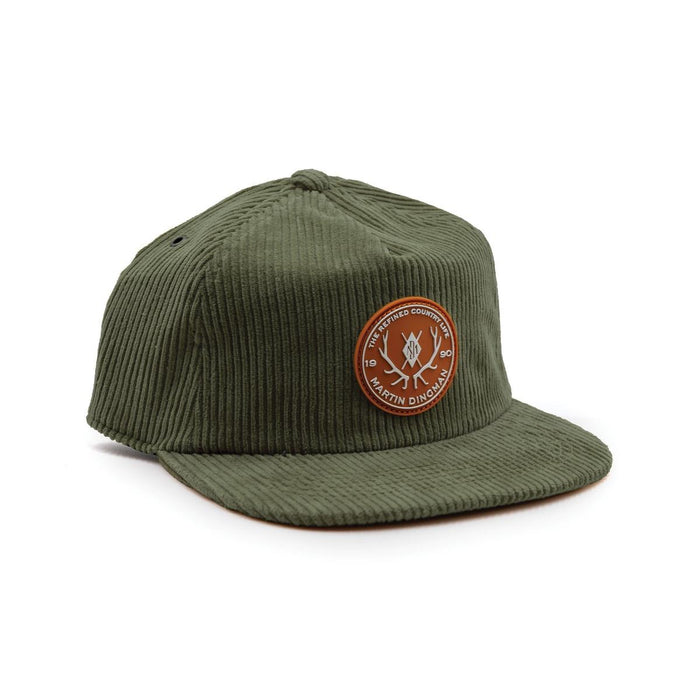 Olive green six-wale cotton corduroy cap featuring a round leather patch with Martin Dingman branding and an adjustable metal slide.