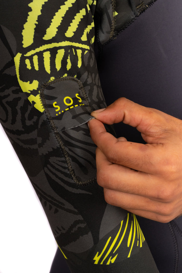 A hand opens a small neoprene S.O.S. pocket on the Waihana Men's Lime Fishbone Long Sleeve Spring Suit, featuring a striking black and neon yellow fishbone graphic print.