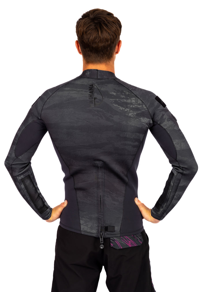 Rear view of a male model wearing the Waihana Men's Tropicam Black rear-zip neoprene surf top, featuring dark camouflage print, reinforced elbow panels, and a pink accent panel at the lower back zipper pull.