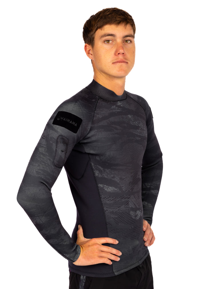 Male model wearing the Waihana Men's Tropicam Black rear-zip neoprene surf rashguard top with dark camouflage pattern and Waihana logo patch on the left shoulder, shown in a three-quarter studio pose.