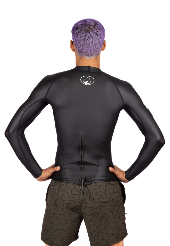 Back view of a male model wearing the Waihana Men's WAI-FLEX long-sleeve black surf top impact suit, showing the Waihana logo on the upper back and a back zipper detail, paired with olive patterned board shorts.