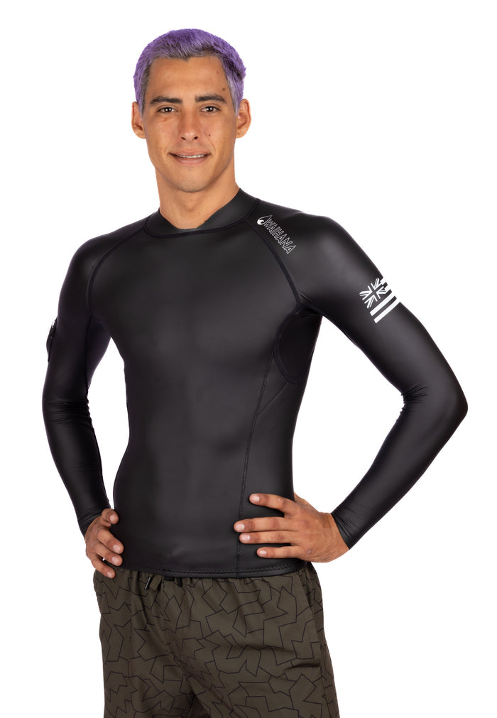 Male model with purple hair wearing a black Waihana Men's WAI-FLEX long-sleeve surf top impact suit, standing with hands on hips against a white background.